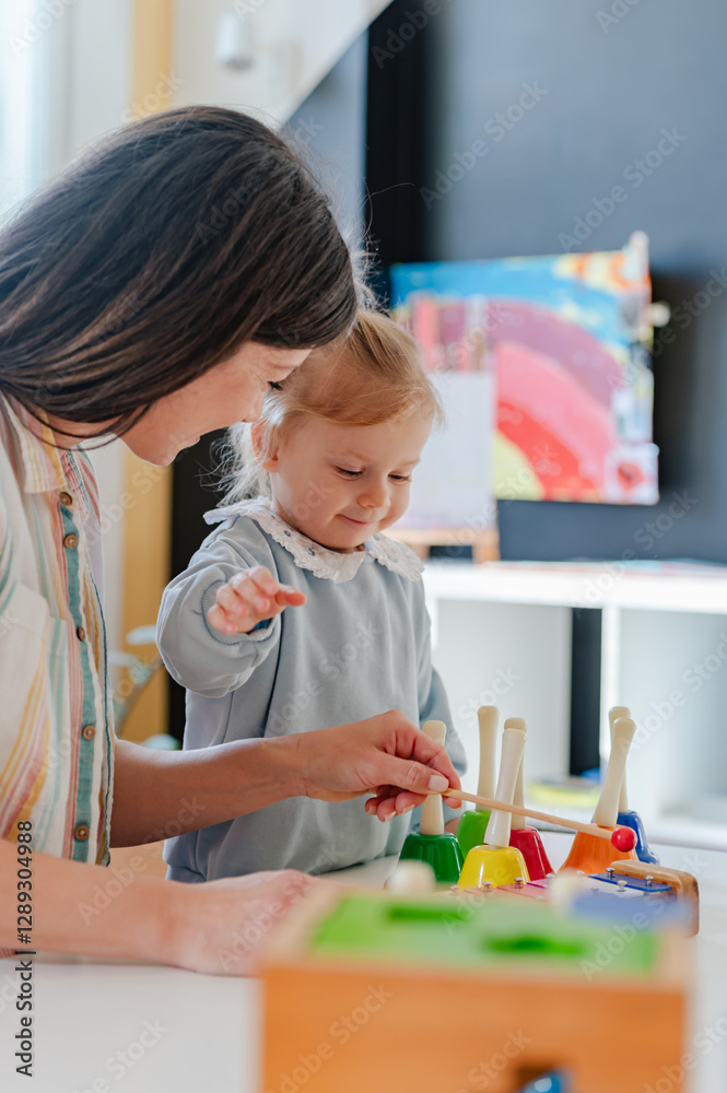 Fototapeta premium A smiling young woman and a little girl engage in a fun educational activity, playing with musical toys in a bright, cheerful indoor setting
