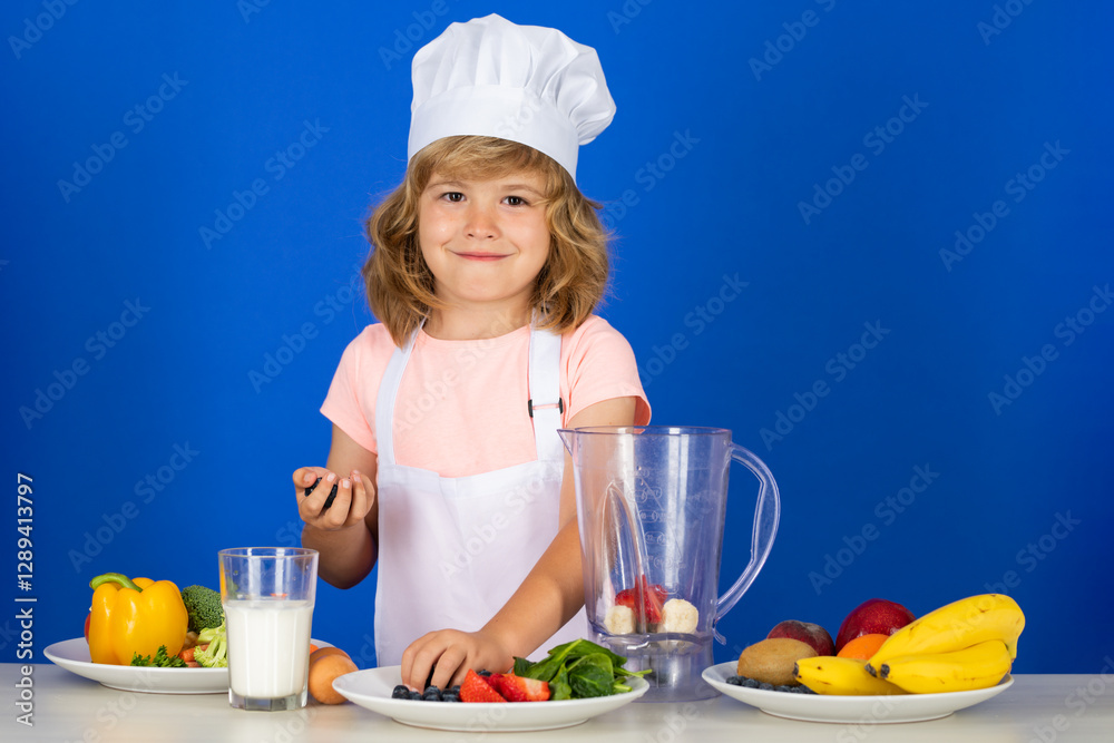 Kid boy in chef hat and apron cooking smoothie preparing meal. Little cook with vegetables at kitchen. Natural kids food. Kid boy in chef hat and apron cooking smoothie preparing meal. Little cook with vegetables at kitchen. Natural kids food.