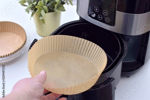 Fotografie A woman places a paper disposable liner into a deep fryer