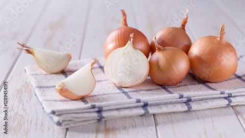 half an onion and a whole yellow onions on a light kitchen table. Yellow onions on a wooden table.