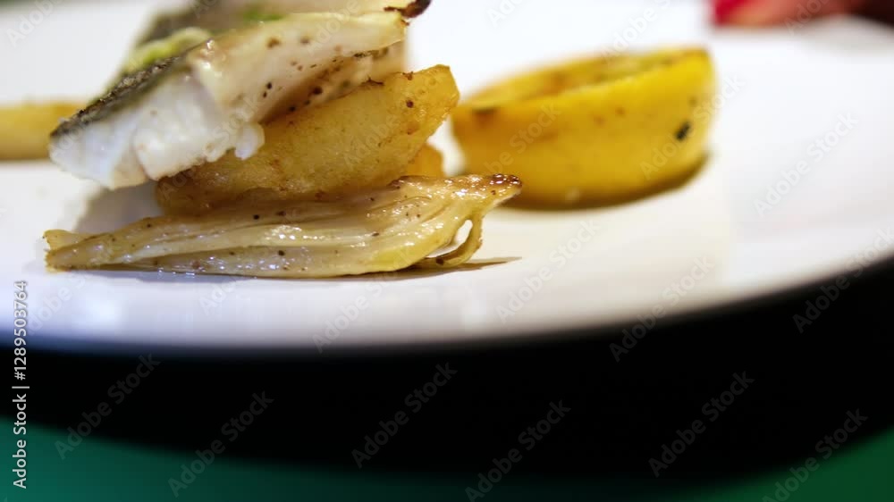 Close up haddock's plate on a white plate on the table of a fancy restaurant. Grilled white fish dish Close up haddock's plate on a white plate on the table of a fancy restaurant. Grilled white fish dish