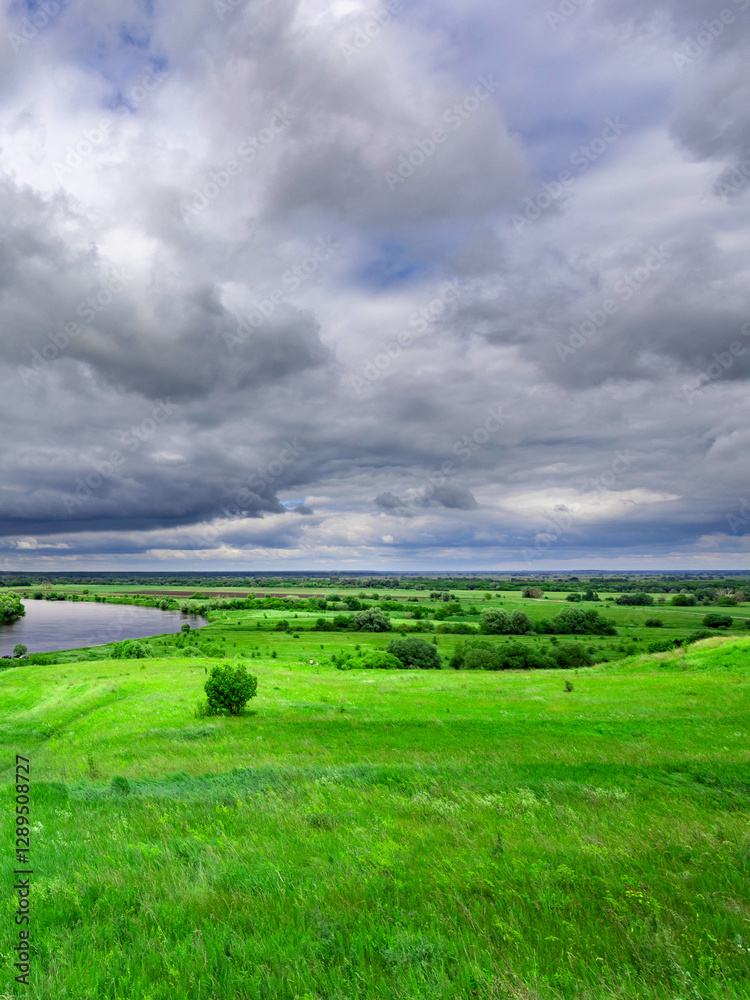 Naklejka premium Cloudy sky with a green field in the background