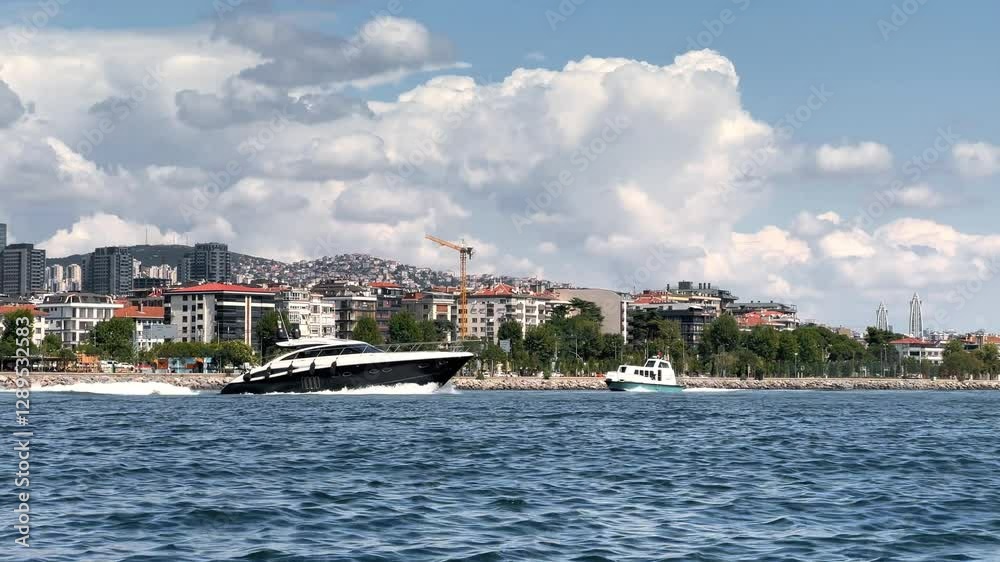 A sleek yacht speeding through water, leaving a trail of foam behind. Istanbul Küçükyalı can be seen with its coastal cityscape and hills densely covered with buildings under a cloudy sky
A sleek yacht speeding through water, leaving a trail of foam behind. Istanbul Küçükyalı can be seen with its coastal cityscape and hills densely covered with buildings under a cloudy sky