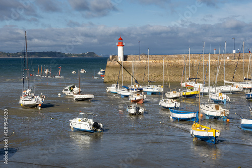 Yachts at low tide and lighthouse in harbor of Erquy, Brittany, France