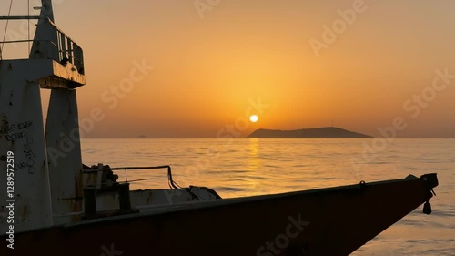 Sunset over the calm sea, with a shipwreck silhouette creating a striking contrast. Golden sunlight reflects on the rippling water, highlighting the serene, tranquil environment. Timelapse, Istanbul, 