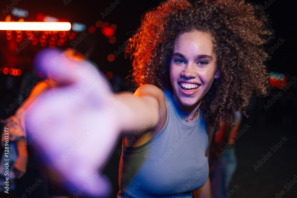 Fototapeta premium Happy young woman reaching for the camera at a concert