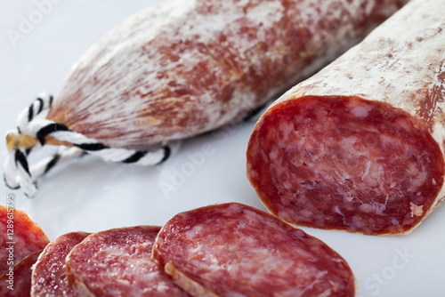Catalan sort of popular Spanish Longaniza sausage from minced pork with cut slices on white surface