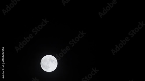 Full moondown through the clouds on dark blue night sky. Timelapse moonscape
