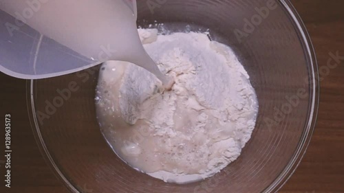 Water poured over white flour in a bowl. Pour water into a bowl with flour and yeast. Making bread dough. Knead flour and water.