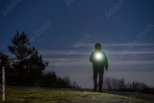 Obraz na płótnie Human standing outdoor at night with flashlight and hoodie on head