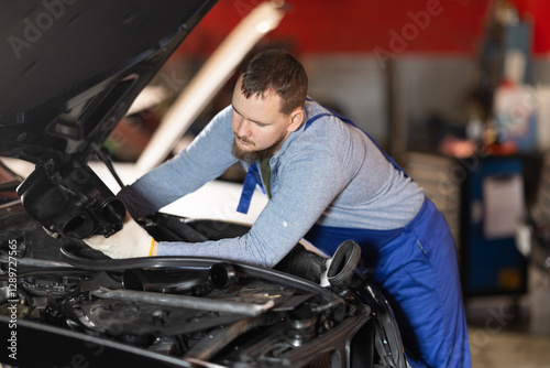 Qualified mechanic checks the condition of the engine, the amount of oil and the mechanics of the car by opening the hood. Car service employee looks at the condition of the car engine photo