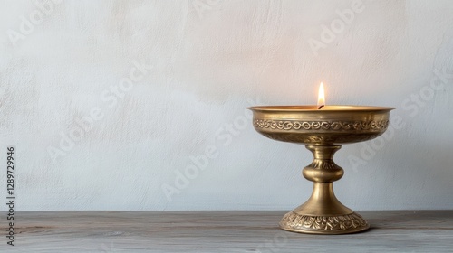 Brass candleholder burning, wood table, textured wall