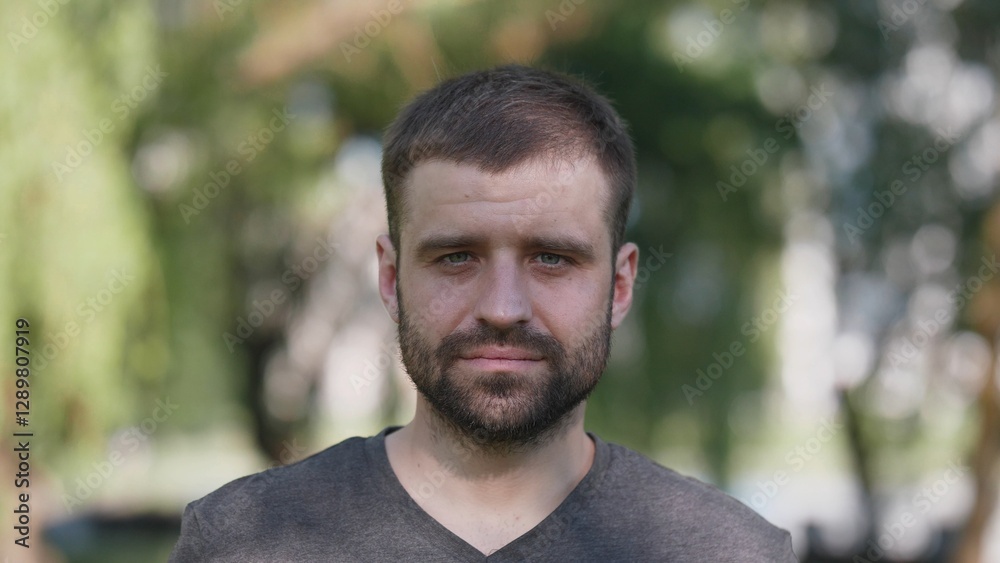 A relaxed portrait showcasing a young man, positioned against a vibrant and lush green background scenery A relaxed portrait showcasing a young man, positioned against a vibrant and lush green background scenery