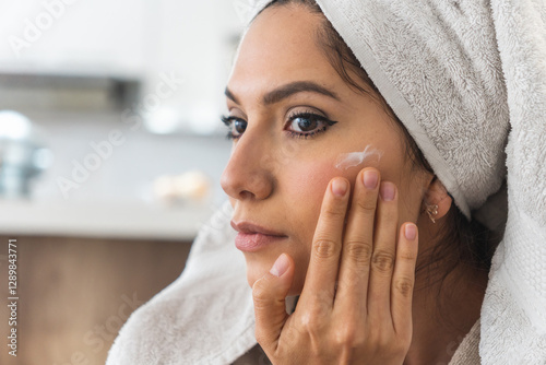 Close-up of a woman putting cream on her face to take care of her skin