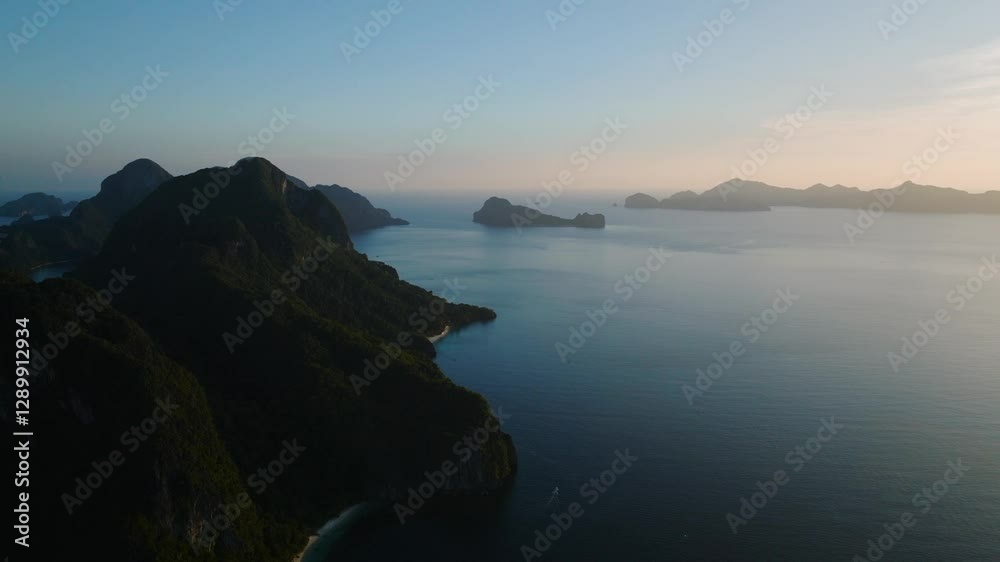 A towering cliff dominates the foreground, covered in lush greenery. Dusky skies in El Nido, Palawan, Philippines. A towering cliff dominates the foreground, covered in lush greenery. Dusky skies in El Nido, Palawan, Philippines.