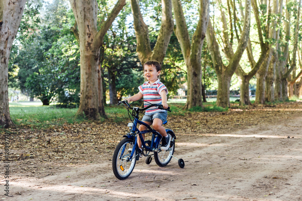 Smiling little boy riding a bicycle in the park. Smiling little boy riding a bicycle in the park.