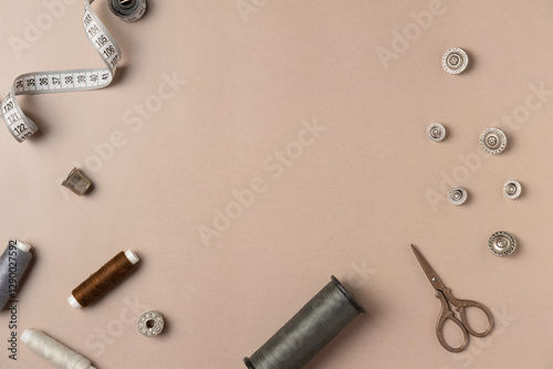 Sewing accessories frame on beige background. Flat lay, top view. Copy space