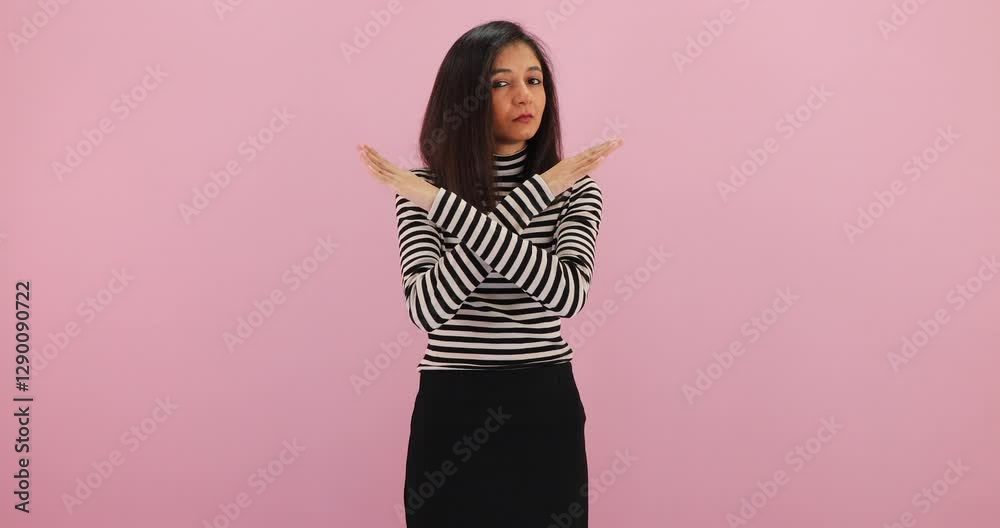 Young woman crossing her hands showing no, refusal, prohibition sign isolated over pink background.