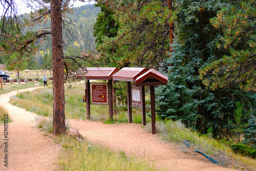 Trail with informational signs in a forested area of nature park.
