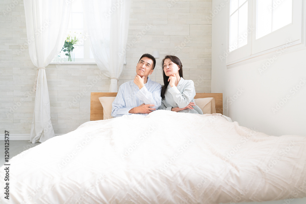 Fototapeta premium 起きてベッドの上で会話をする夫婦