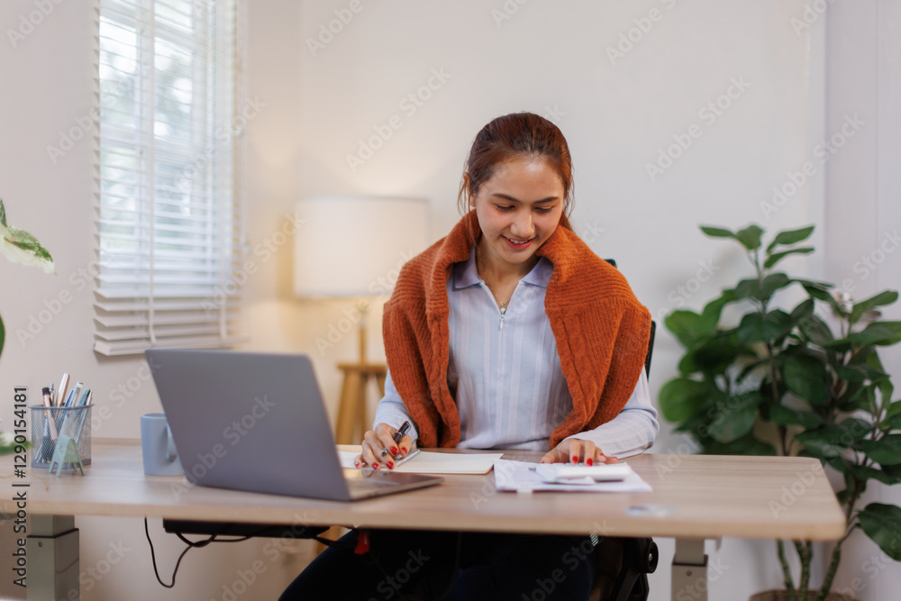 Happy young asian woman accountant working documents on laptop and phone desk using calculator for calculate finance report in home office