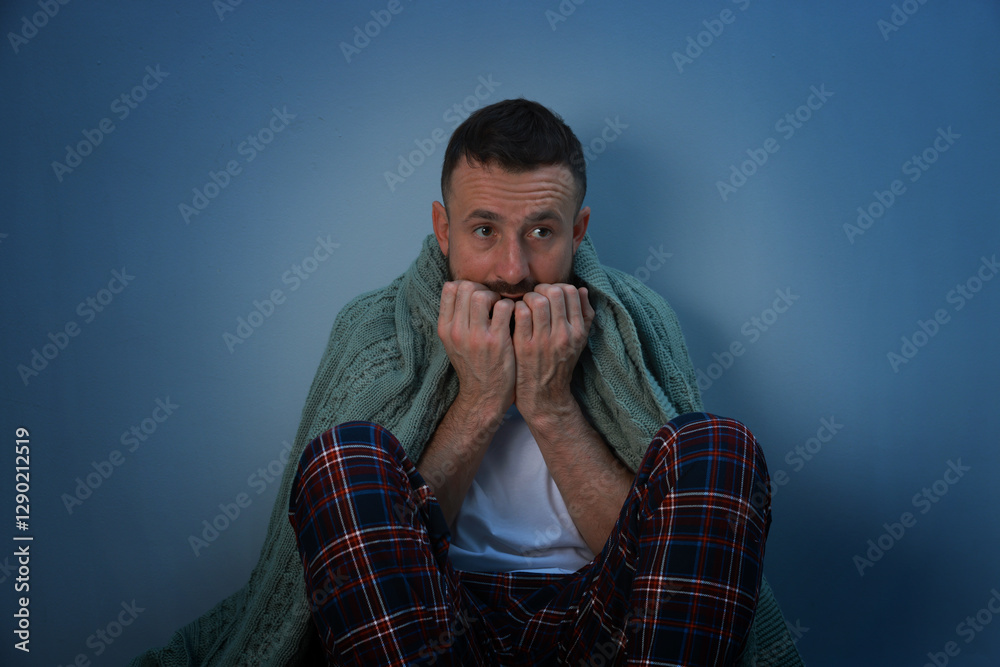 Fear of darkness. Scared man with blanket on light grey background Fear of darkness. Scared man with blanket on light grey background