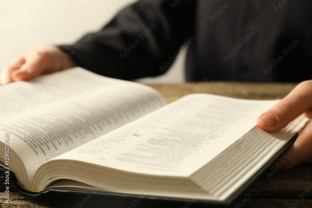 Woman with Holy Bible in English language at wooden table, closeup Woman with Holy Bible in English language at wooden table, closeup