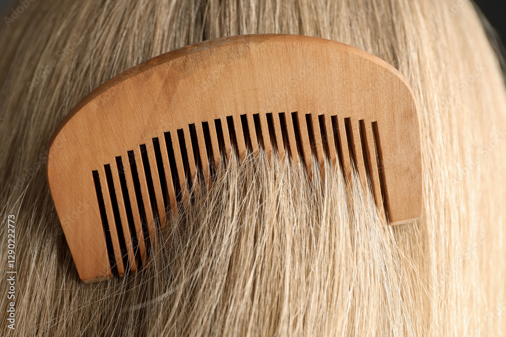 Obraz premium Brushing hair with wooden comb, closeup view
