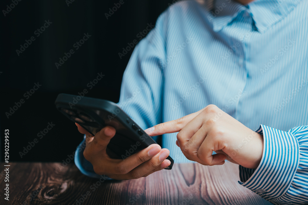 Close-up of Hand Using Smartphone on Wooden Table in Soft Light, Business concept Close-up of Hand Using Smartphone on Wooden Table in Soft Light, Business concept