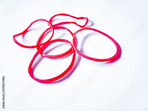 Fotografie Close-up red rubber bands against a plain white background