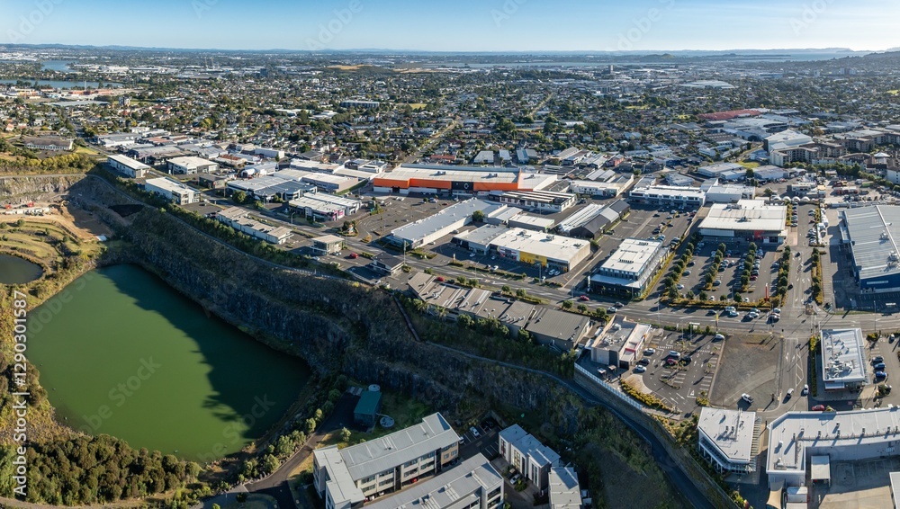 Fototapeta premium Aerial view of a bustling shopping center and residential area. Retail stores, parking lots, and homes are visible. Urban development. STONEFIELDS, AUCKLAND, NZ