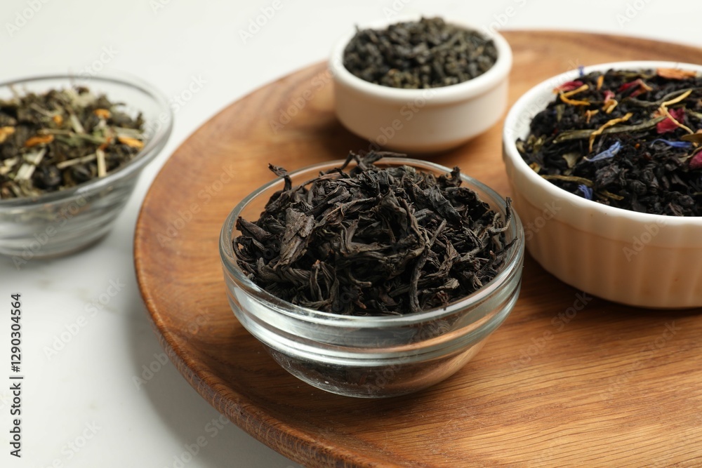 Different dry tea leaves in bowls on white marble table, closeup Different dry tea leaves in bowls on white marble table, closeup