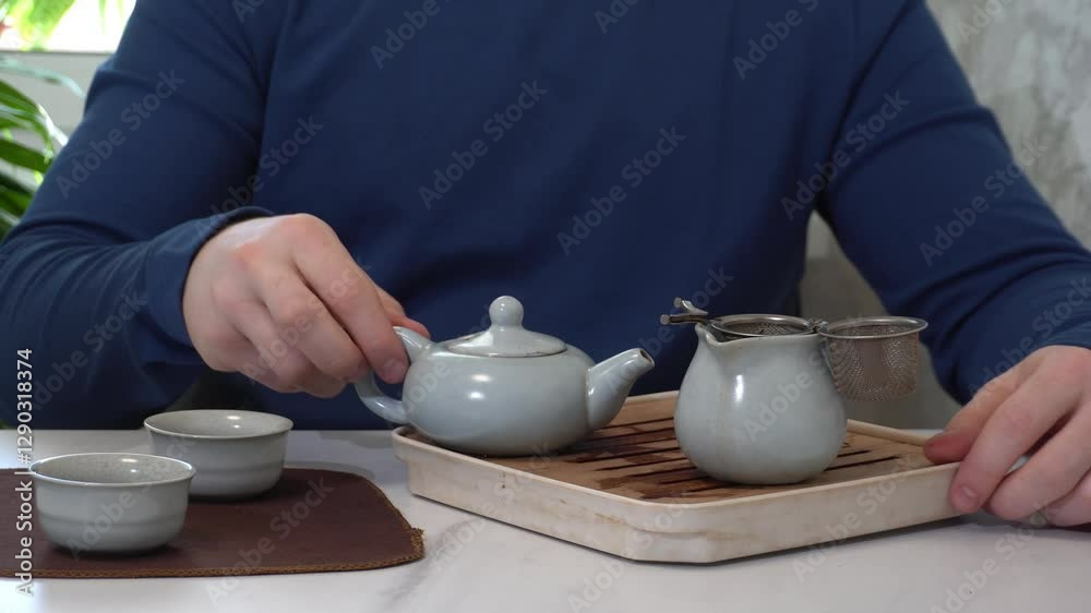 Man brewing chinese tea using traditional teapot and small cups