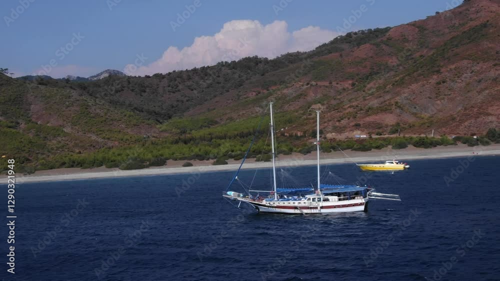 Typical Turkish sailing vessel, gulet on deep blue waters, surrounded by scenic mountains, Karaincir beach, Turkey. Aerial lateral view Typical Turkish sailing vessel, gulet on deep blue waters, surrounded by scenic mountains, Karaincir beach, Turkey. Aerial lateral view
