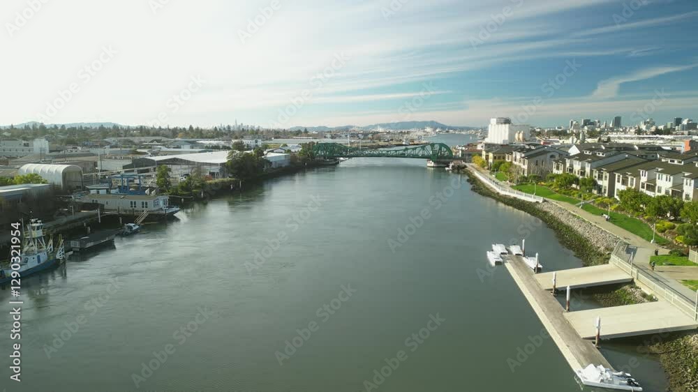 An aerial drone view captures the Tidal Canal and Park Street Bridge in Alameda, showcasing calm waters and urban charm. An aerial drone view captures the Tidal Canal and Park Street Bridge in Alameda, showcasing calm waters and urban charm.