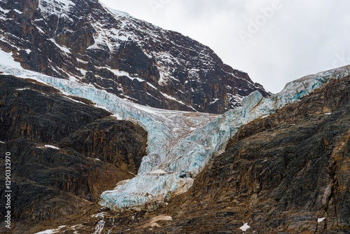 Canvas Print A stunning glacier flows down a rocky mountain slope, beautifully contrasting with the rugged landscape and showcasing the powerful forces of nature and climate change