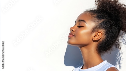 African American girl with closed eyes enjoying the sun, white background from the side. 
