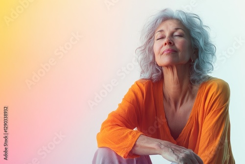 A serene older woman with silver hair, eyes closed, wearing an orange shirt, enjoys a moment of peace and tranquility.