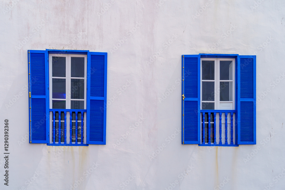 Blue windows and shutters on an old house white wall