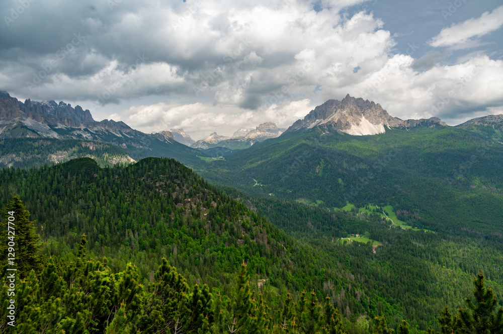 Breathtaking view of forests, mountains, and valleys in the Italian Dolomites (Dolomiti, Dolomiten). Captured from a scenic trail along a rocky ledge. Stunning alpine nature