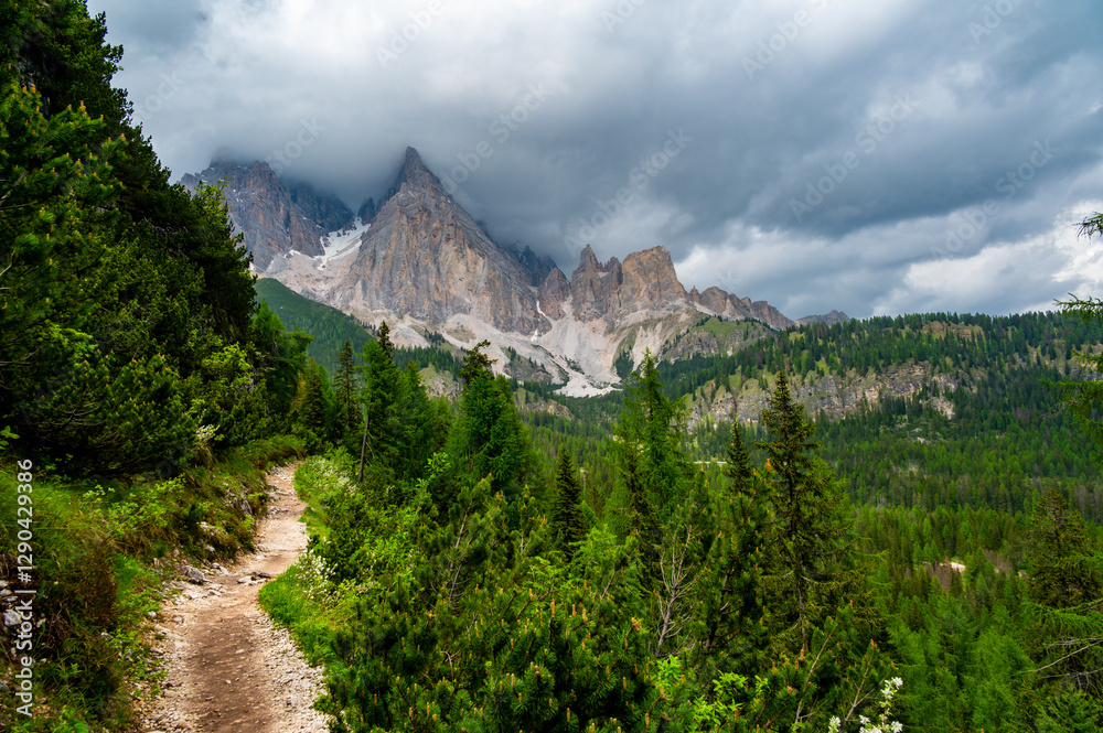 Breathtaking view of forests, mountains, and valleys in the Italian Dolomites (Dolomiti, Dolomiten). Captured from a scenic trail along a rocky ledge. Stunning alpine nature