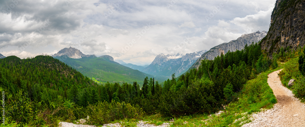 Breathtaking view of forests, mountains, and valleys in the Italian Dolomites (Dolomiti, Dolomiten). Captured from a scenic trail along a rocky ledge. Stunning alpine nature