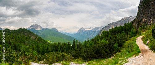 Breathtaking view of forests, mountains, and valleys in the Italian Dolomites (Dolomiti, Dolomiten). Captured from a scenic trail along a rocky ledge. Stunning alpine nature