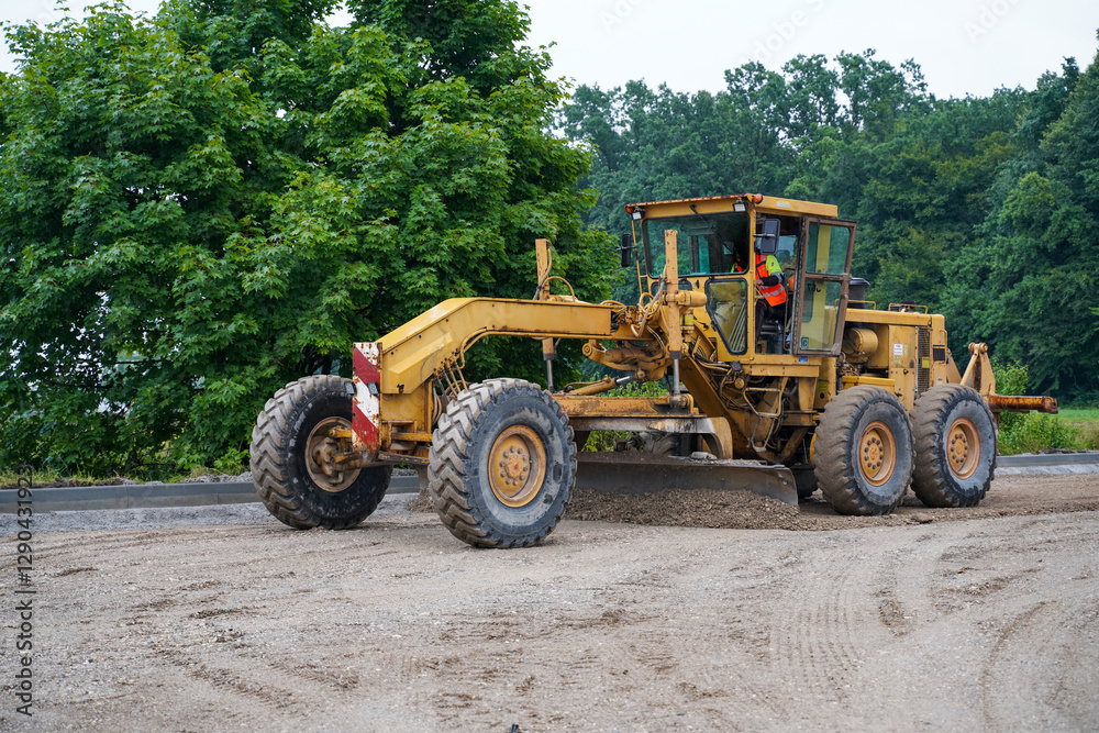 Motor grader smoothing surface for an even platform for new asphalt at highway construction site Motor grader smoothing surface for an even platform for new asphalt at highway construction site