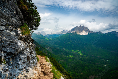 Breathtaking view of forests, mountains, and valleys in the Italian Dolomites (Dolomiti, Dolomiten). Captured from a scenic trail along a rocky ledge. Stunning alpine nature