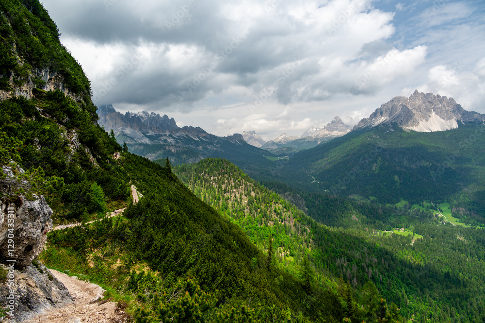 Breathtaking view of forests, mountains, and valleys in the Italian Dolomites (Dolomiti, Dolomiten). Captured from a scenic trail along a rocky ledge. Stunning alpine nature