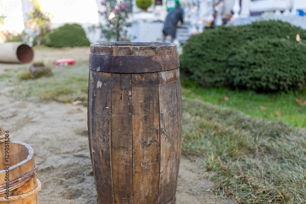 Large wooden barrel sits on the ground in a grassy area Large wooden barrel sits on the ground in a grassy area
