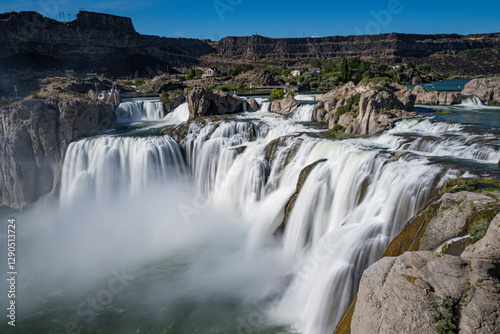 A breathtaking view of powerful waterfalls cascades through a natural setting, showcasing the raw energy and beauty of water in motion amidst lush greenery.