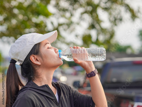 Lifestyle Health care. Asian woman in workout clothes lifting a water bottle to drink in a park. People who drinking water after exercising and feel refreshed. Benefit helps nourish and cleanse body