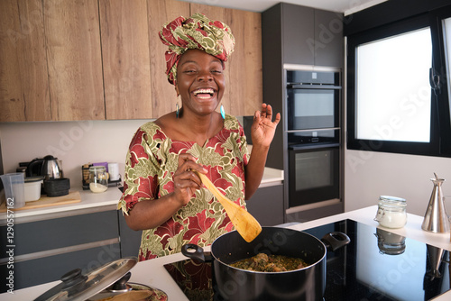 African woman cooking traditional Okra Soup in modern kitchen photo